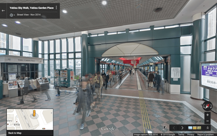 Inside the boxy green structure.  It also holds an elevator for reaching the underground arcade from Ebisu Garden Place.